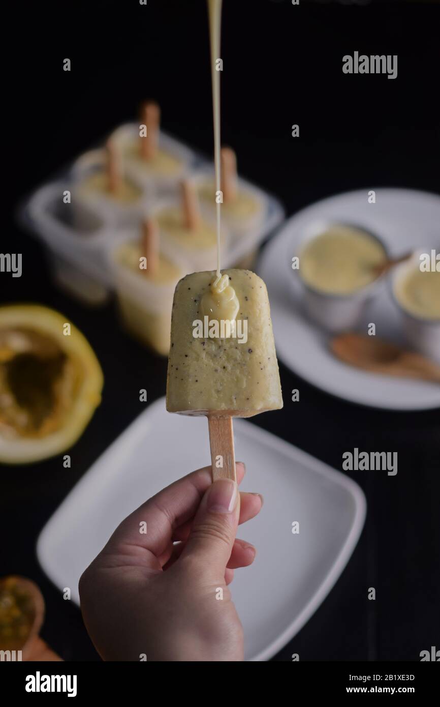 tomando a mano helado de fruta de la pasión con leche condensada y detrás  de un molde de helado y pedazos de fruta de la pasión Fotografía de stock -  Alamy