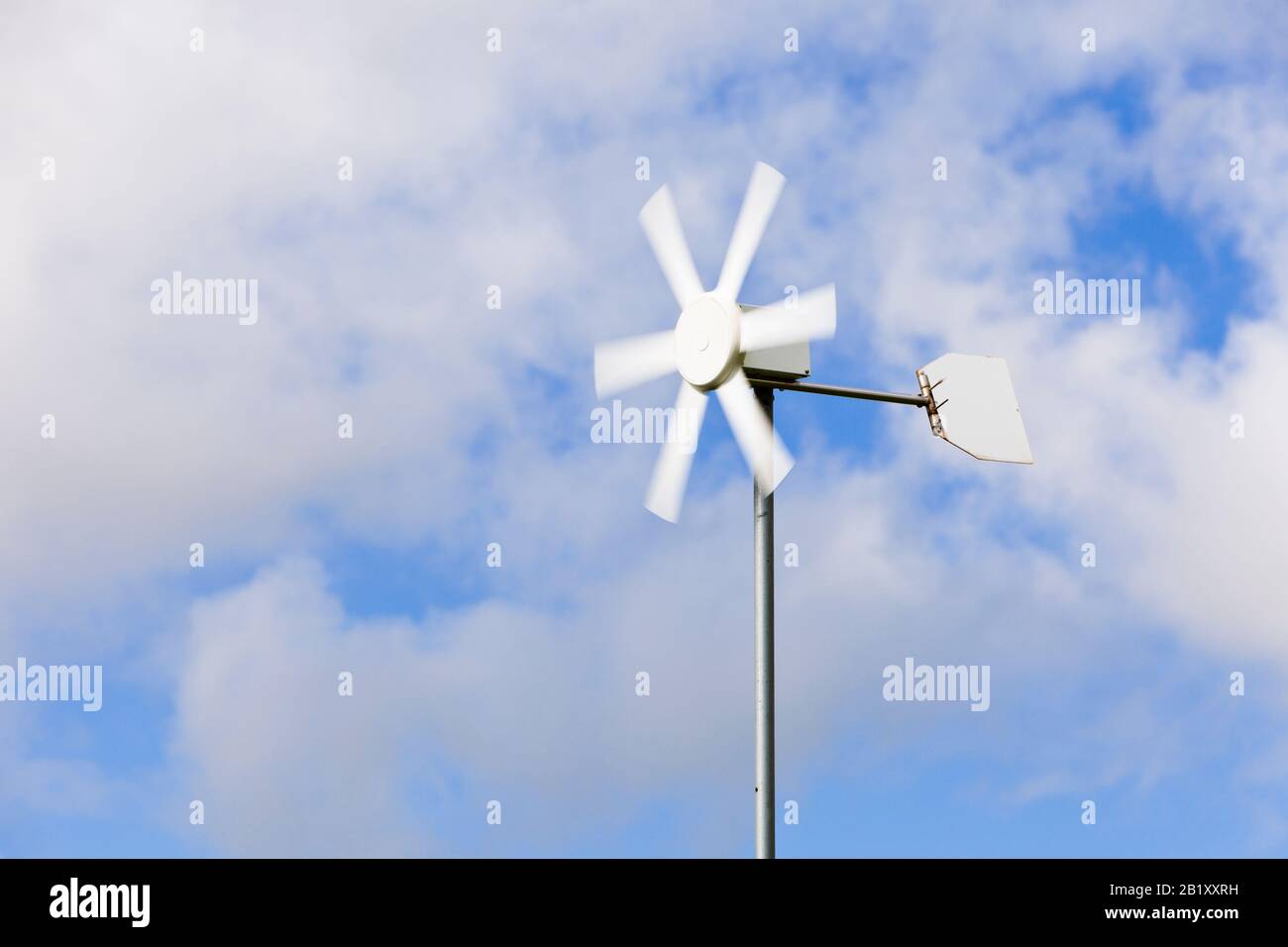Pequeña turbina eólica doméstica contra un cielo azul, Inglaterra, Reino Unido Foto de stock