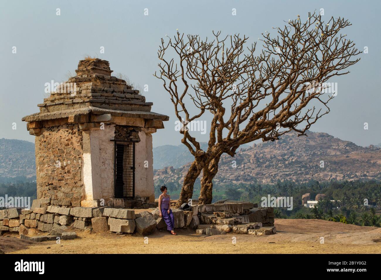 Chica turístico cerca de un antiguo edificio con un árbol. El Grupo de monumentos en Hampi fue el centro del Imperio Vijayanagara hindúes en el estado de Karnataka Foto de stock