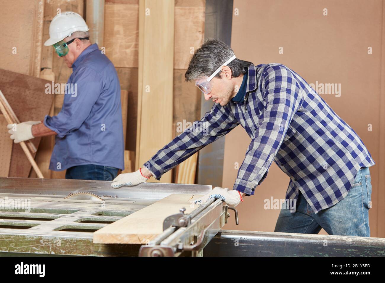 Carpenter corta madera con una sierra circular en una carpintería Foto de stock