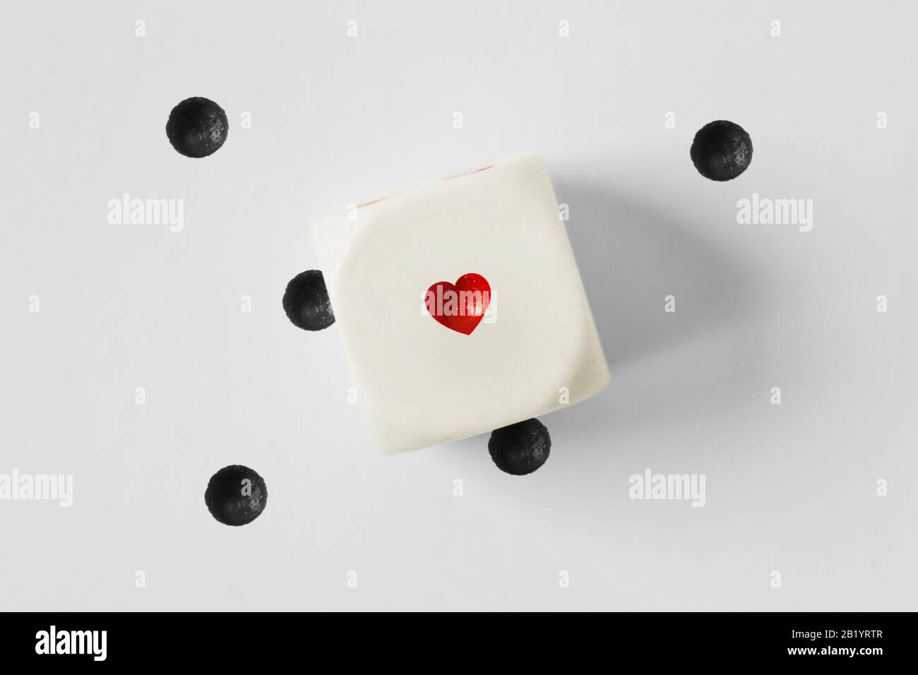 Dados con corazón y puntos negros perdidos sobre fondo blanco Foto de stock