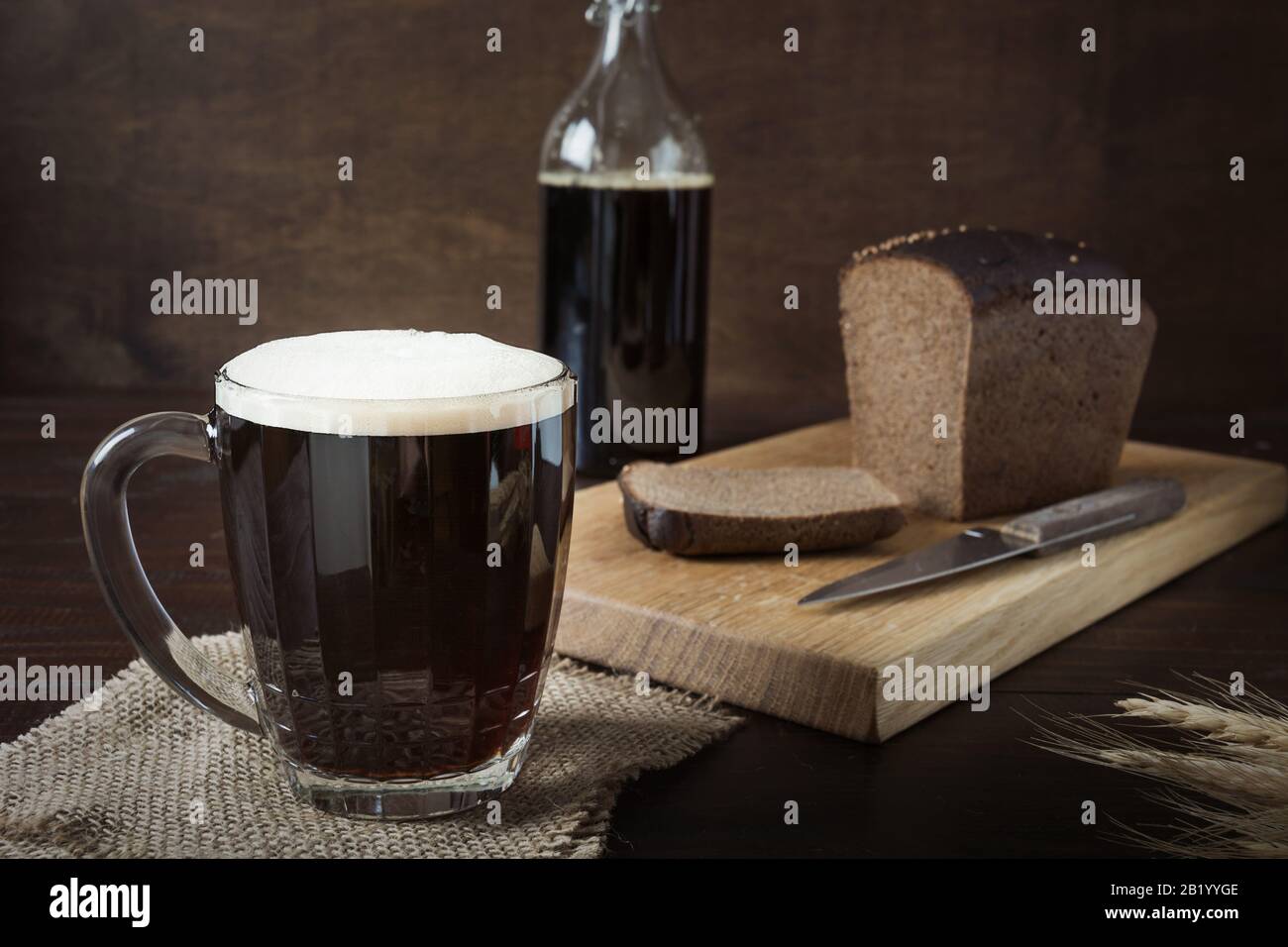 Bebida rusa fermentada kvass de pan de centeno en taza especial de medio litro sobre fondo oscuro. Primer plano. Foto de stock