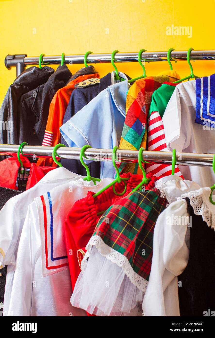 Cremallera con muchos trajes de vacaciones para niños en perchas en la sala  de exposición de moda de los niños. Servicio de alquiler en la tienda de  ropa Fotografía de stock -