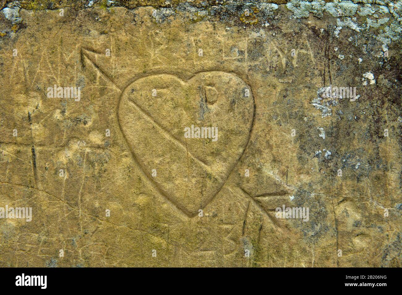 Un corazón y una flecha esculpidos en la pared de la cabaña final en Arlington Row, en Arlington cerca de Bibury en el Cotswolds AONB, Gloucestershire. Foto de stock