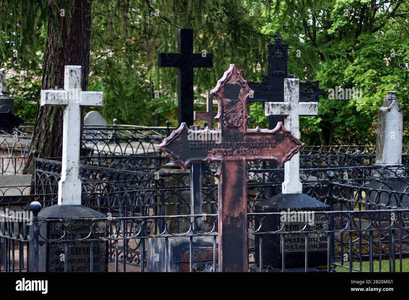 Hierro fundido y cruces de mármol en tumbas valladas en el cementerio