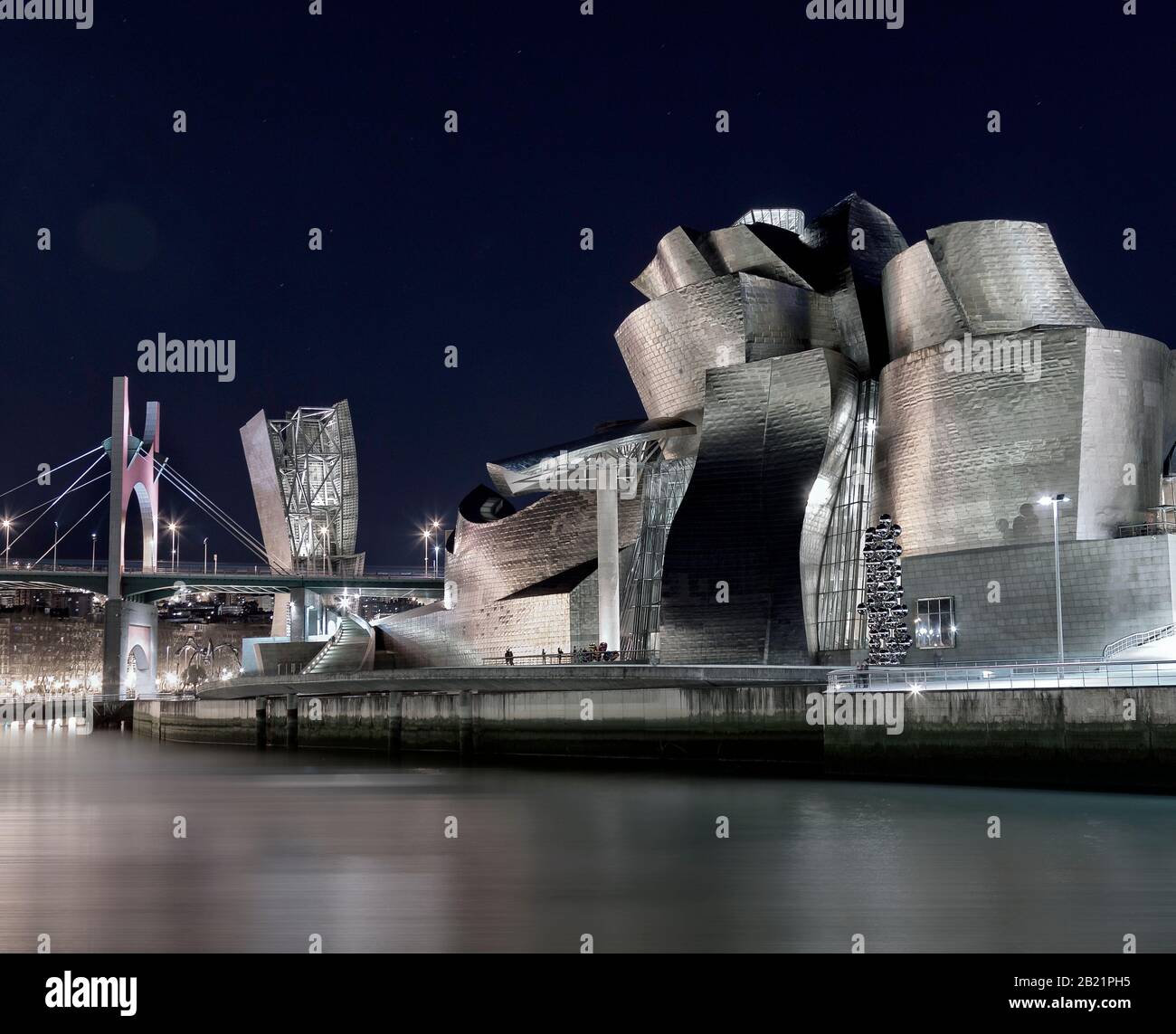 Vista nocturna del museo Guggenheim sobre el estuario del río Nervion. Bilbao, España Foto de stock