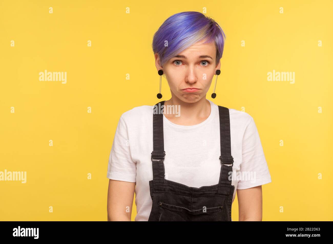 Retrato De Una Joven Mujer Hipster Disgustada Con Pelo Corto Tenido De Violeta En Overoles De Denim Mirando A La Camara Con Expresion Ofendida Resentida Labios Fruncidos Fotografia De Stock Alamy