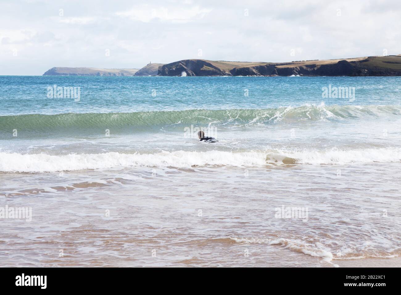 Un niño espera una ola para rodar en la playa de surf de Harlyn Bay en North Cornwall, Reino Unido. Foto de stock