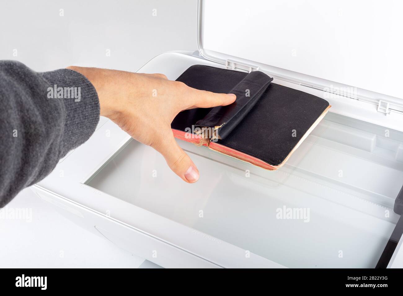 Hombre fotocopia, escaneo de un libro viejo en una fotocopiadora abierta  casa impresora Vista superior, la mano de colocar un pequeño libro sobre la  copiadora de cristal superficie Archivin Fotografía de stock -