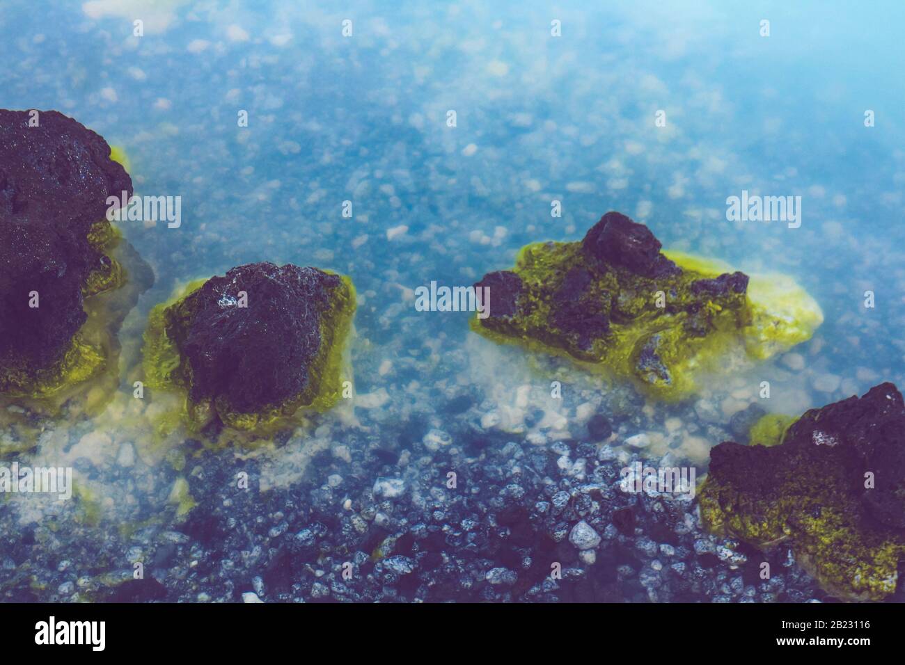 Detalle de las aguas lechosas y rocas con manchas de azufre de la laguna azul de Islandia, un manantial caliente con sílice utilizado para tratamientos de spa. Foto de stock