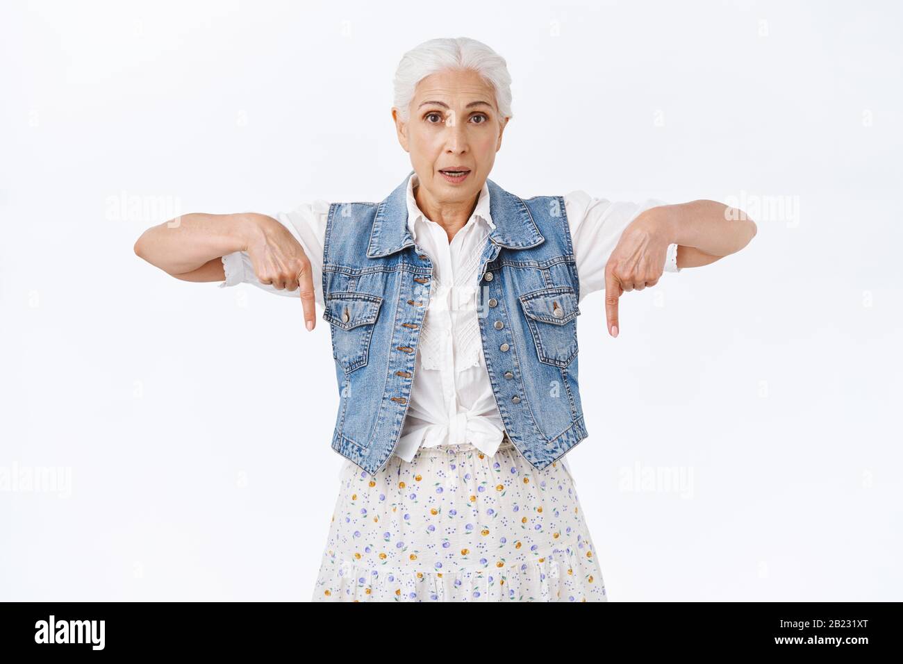Curioso Cuestionado E Intrigado Encantadora Mujer Mayor Con El Pelo Gris Llevar Chaleco Vaquero Vestido Senalar Los Dedos Hacia Abajo Mostrar El Espacio Inferior De Copia Y Fotografia De Stock Alamy