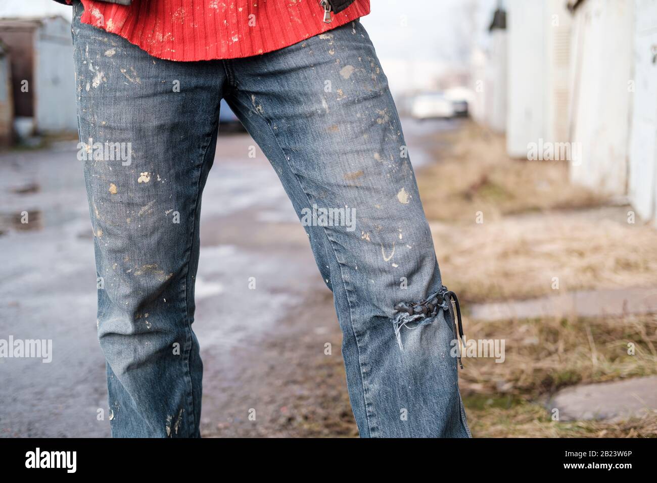 Las piernas de un hombre en jeans de trabajo sucio, con un agujero en su  rodilla, que está atado con un cordón Fotografía de stock - Alamy