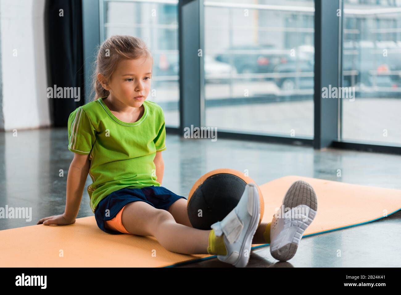 Niño con pelota en las piernas sentado en la alfombrilla del gimnasio  Fotografía de stock - Alamy