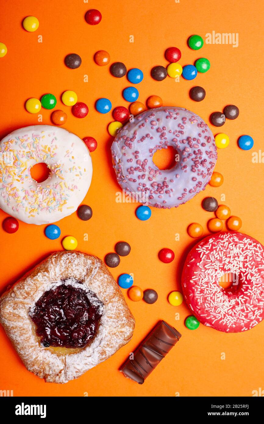 dulces planos yacen. donuts de caramelo sobre un fondo naranja brillante. Foto de stock