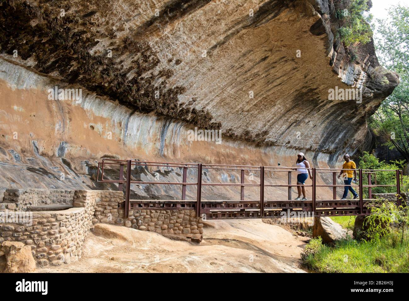 Gente cruzando un puente que entra en la cueva de Liphofung para ver arte rupestre, Lesotho Foto de stock