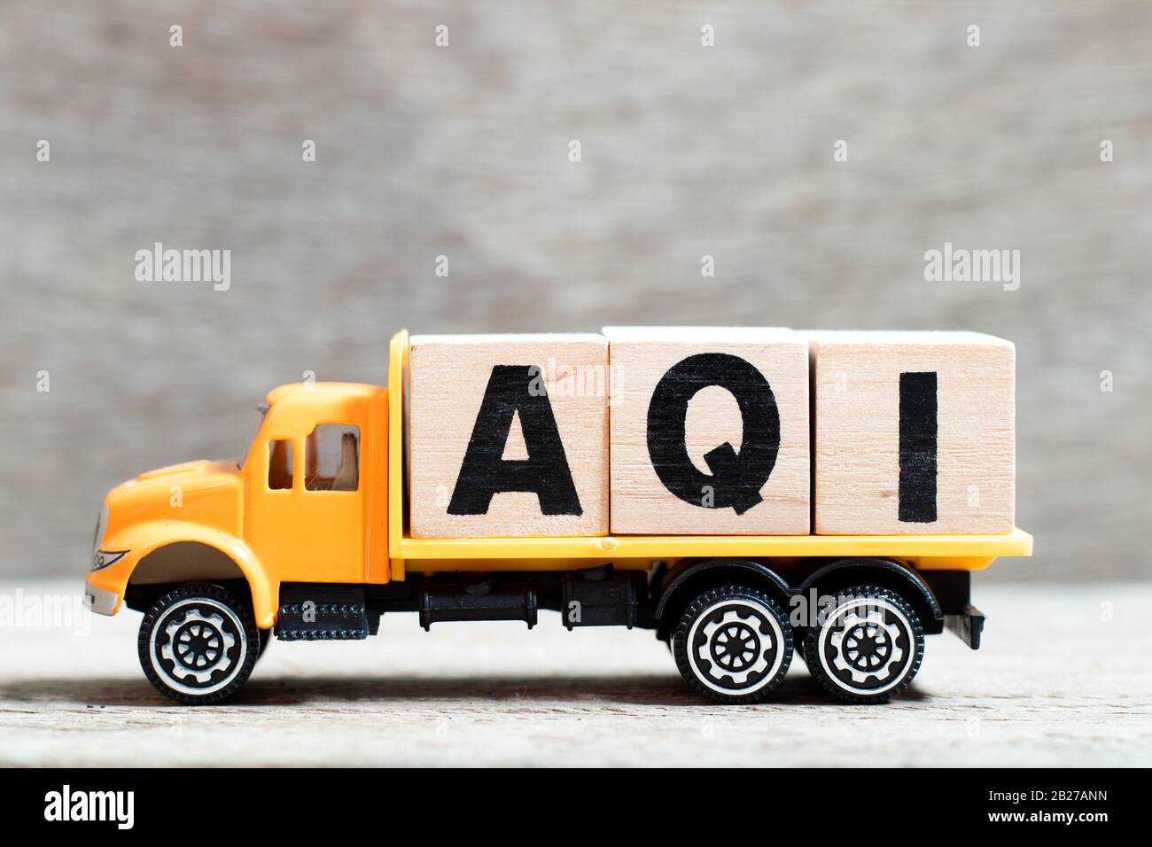 La carretilla mantiene el bloque de letras en la palabra AQI (Índice de calidad del aire) sobre fondo de madera Foto de stock