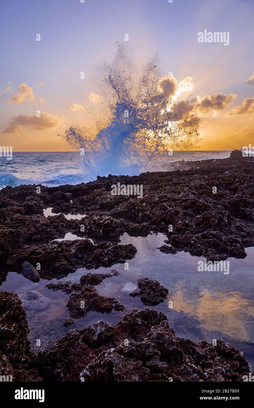 Olas rompiendo en rocas grandes salpicaduras en el blowhole de Gran Caimán Foto de stock