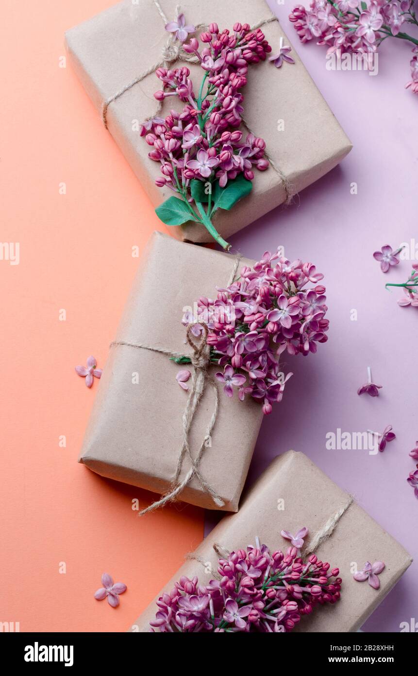 Cajas de regalo hechas a mano envueltas en papel marrón kraft decoradas con  flores lila púrpura sobre un fondo rosa. Fondo creativo de las vacaciones  de primavera Fotografía de stock - Alamy
