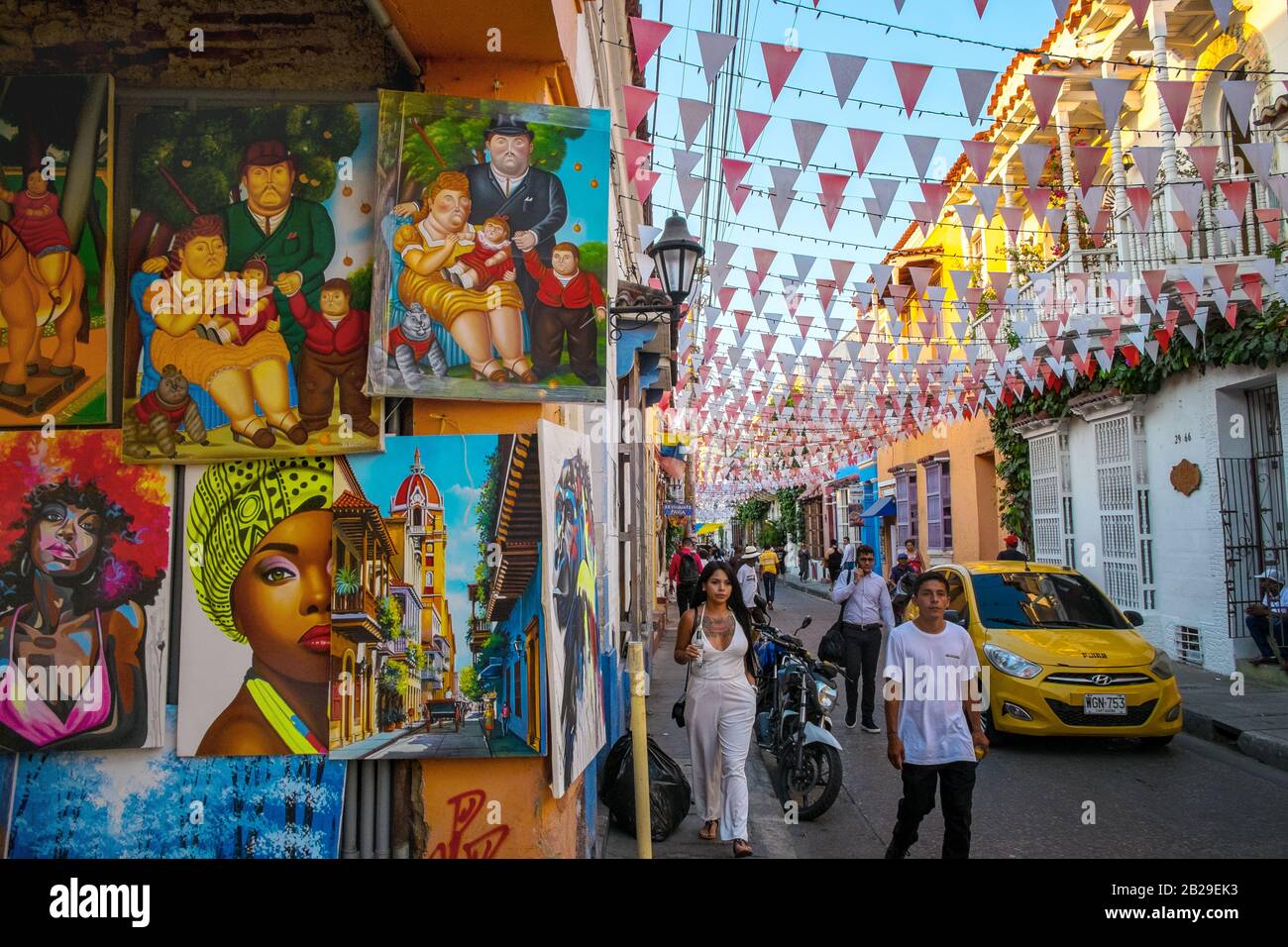 Los peatones caminan por las pinturas para la venta en un estudio artístico en el Barrio Getsemaní, Cartagena, Colombia Foto de stock