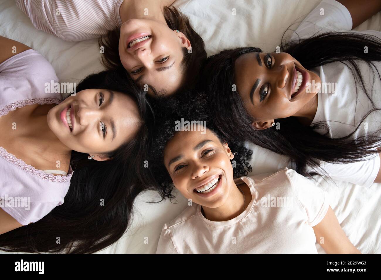 Arriba ver diversas mujeres mejores amigos tumbados juntos en la cama Foto de stock