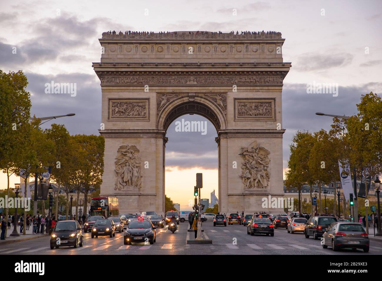 El tráfico al atardecer frente al Arco del Triunfo, uno de los monumentos más famosos de París, Francia Foto de stock
