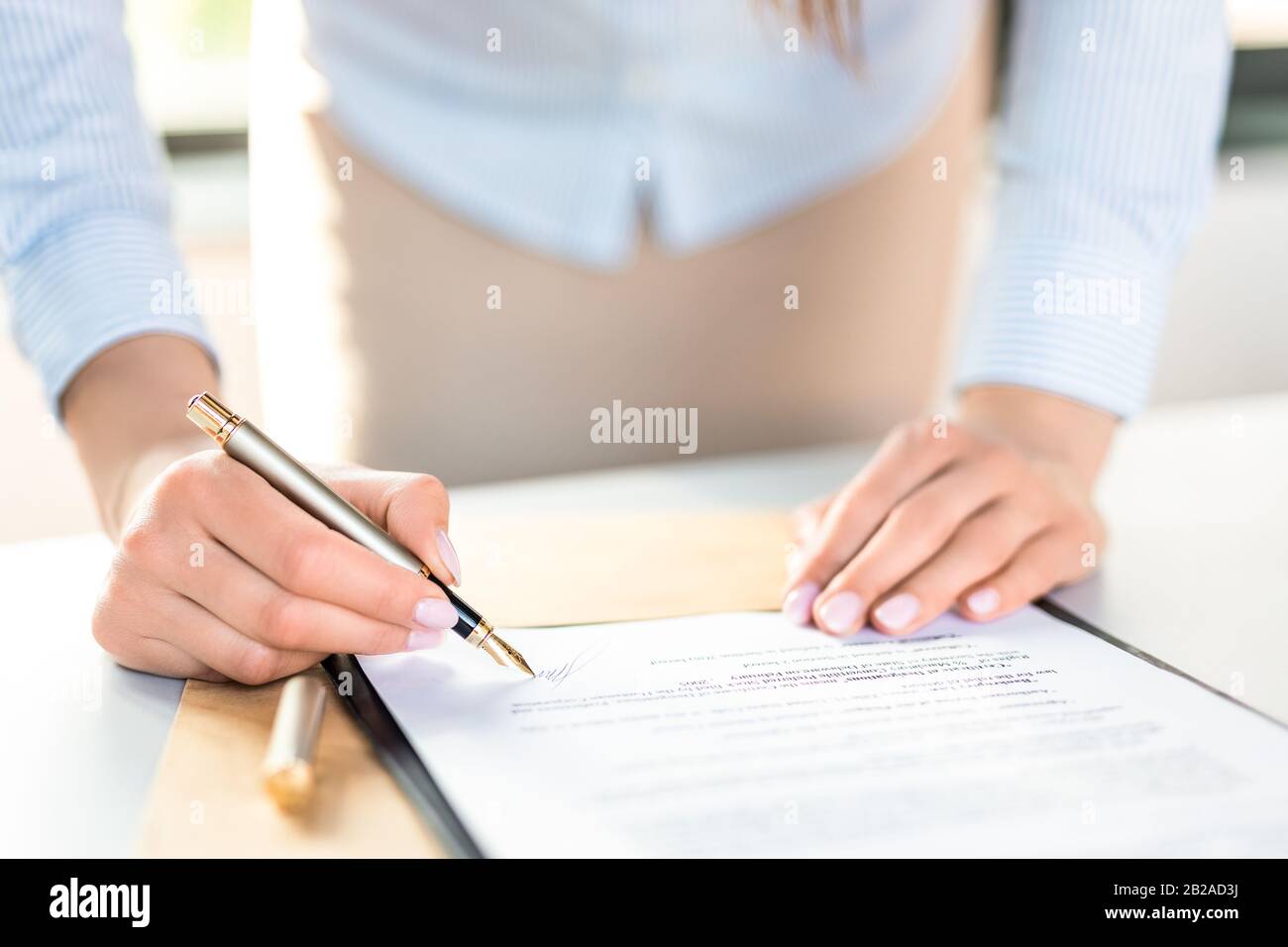 Mujer de negocios firmando el documento del contrato en el escritorio de la oficina, haciendo un reparto. Foto de stock