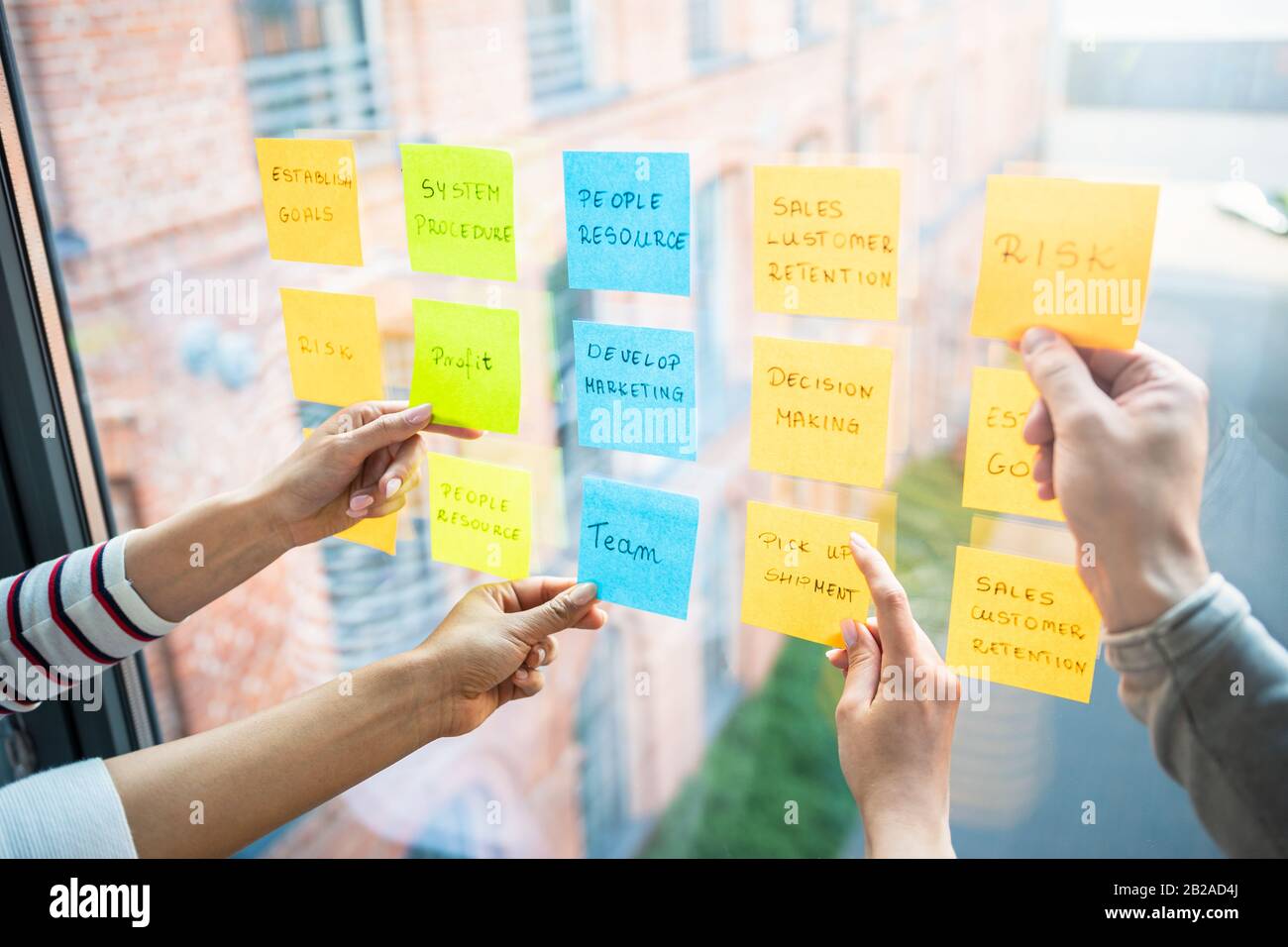 Los empresarios reunidos en la oficina y utilizar post-it Notes para compartir la idea. Concepto de lluvia de ideas. Nota sobre la pared de vidrio. Foto de stock