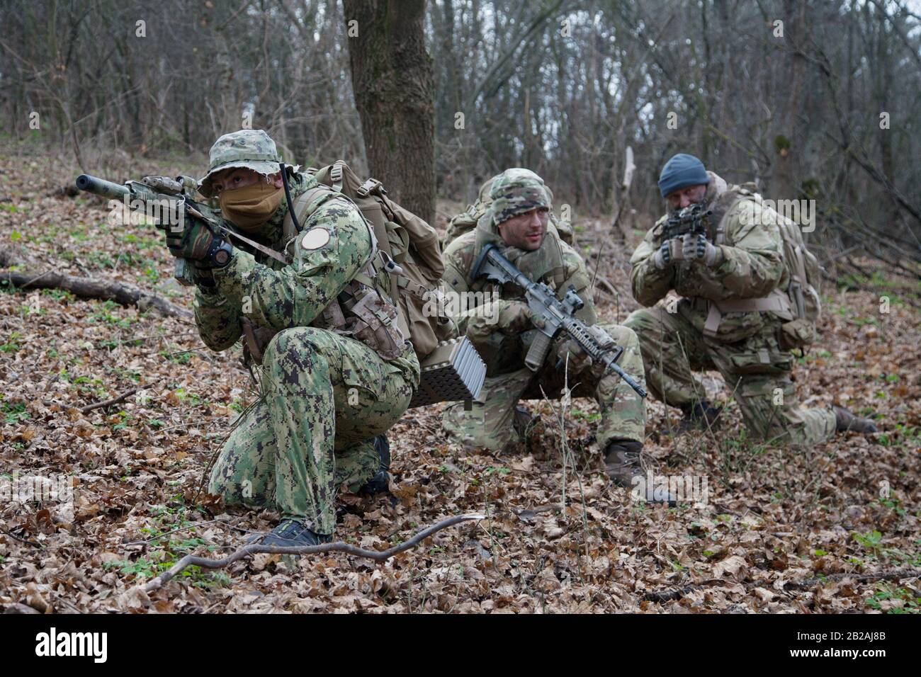 El equipo de soldados militares del ejército llevaba uniformes de camuflaje  y municiones, fusiles de asalto armados, réplicas de ametralladoras,  escondidos en bosques, haciendo emboscada Fotografía de stock - Alamy