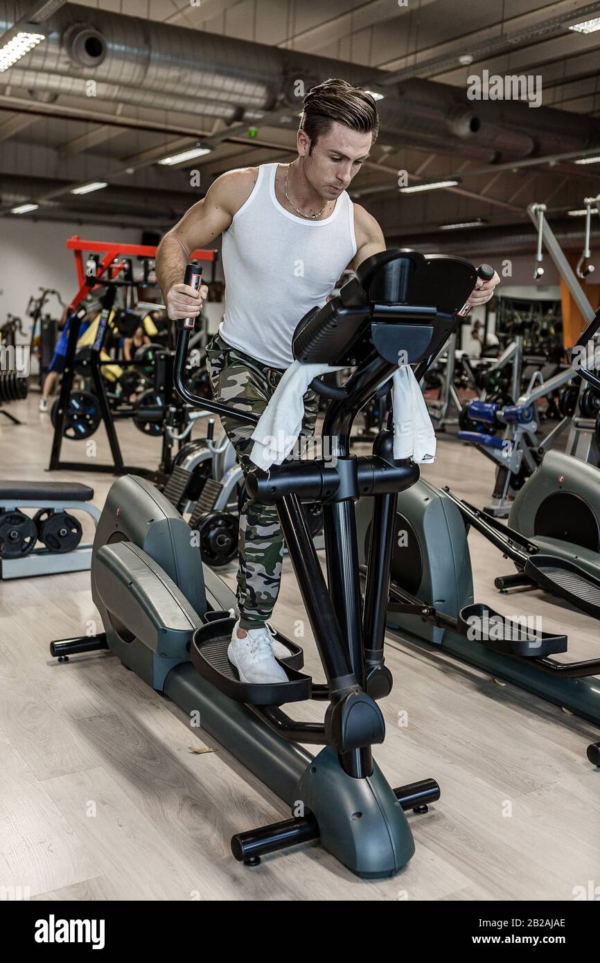 Todo el cuerpo determinado sportswear realizar ejercicio en máquina de paso moderno durante el entrenamiento en el gimnasio. Foto de stock