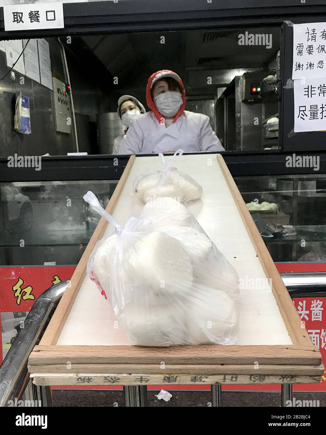 Pekín, China. 2 de marzo de 2020. Una famosa tienda China de dumpling pasa los pedidos a los clientes en espera sobre un pequeño "puente" improvisado debido a la amenaza de difundir el letal coronavirus (Covid-19) en Pekín el lunes 2 de marzo de 2020. El letal y novedoso coronavirus ha matado a más de 3,000 personas en todo el mundo, la mayoría en China. Se han confirmado más de 88,000 casos, con infecciones en más de 56 países y en todos los continentes, excepto la Antártica. Foto de Stephen Shaver/UPI crédito: UPI/Alamy Live News Foto de stock