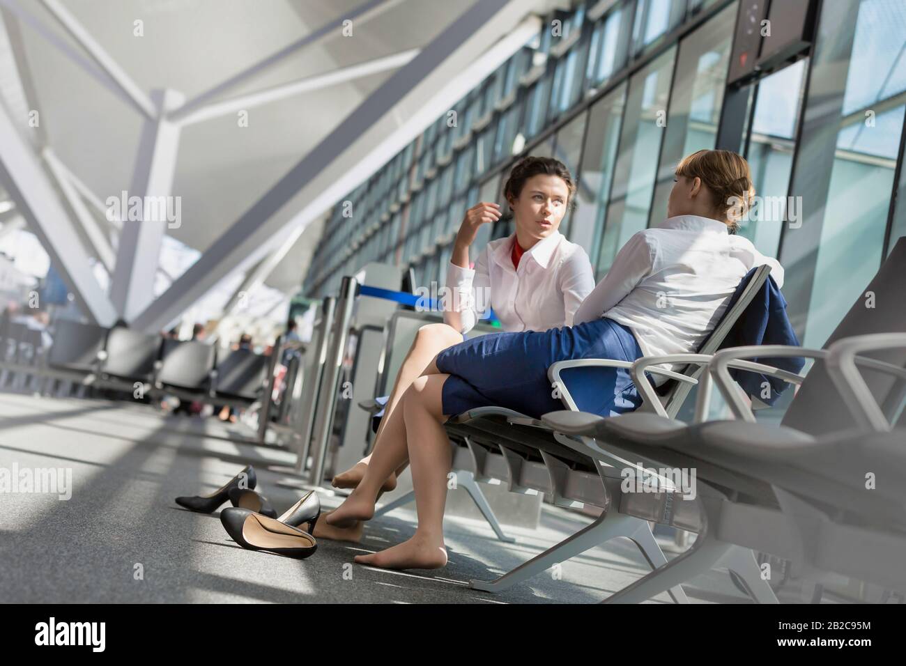 El personal del aeropuerto es joven y atractivo y está sentado mientras habla durante un descanso en el aeropuerto Foto de stock