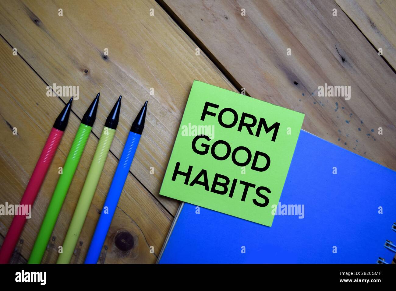 Forma Buenos Hábitos escribir en una nota pegajosa aislada sobre fondo de madera. Foto de stock