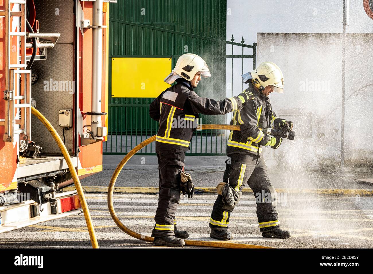 bomberos con una manguera de agua tirando del agua para apagar un incendio  Fotografía de stock - Alamy
