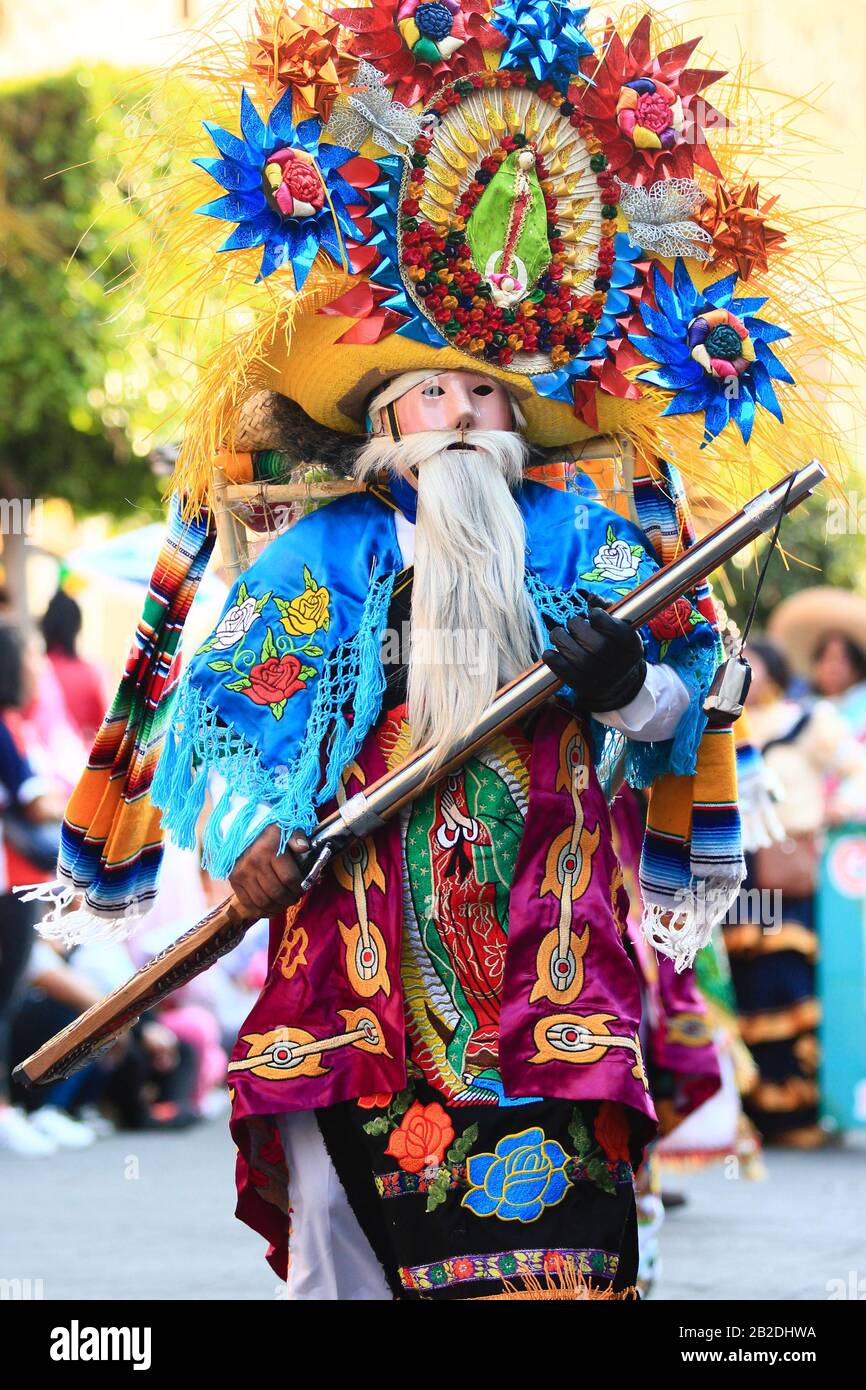 Un bailarín de carnaval mexicano con traje colorido, icono De Nuestra  Señora de Guadalupe como parte de la decoración sostiene una pistola en sus  manos Fotografía de stock - Alamy