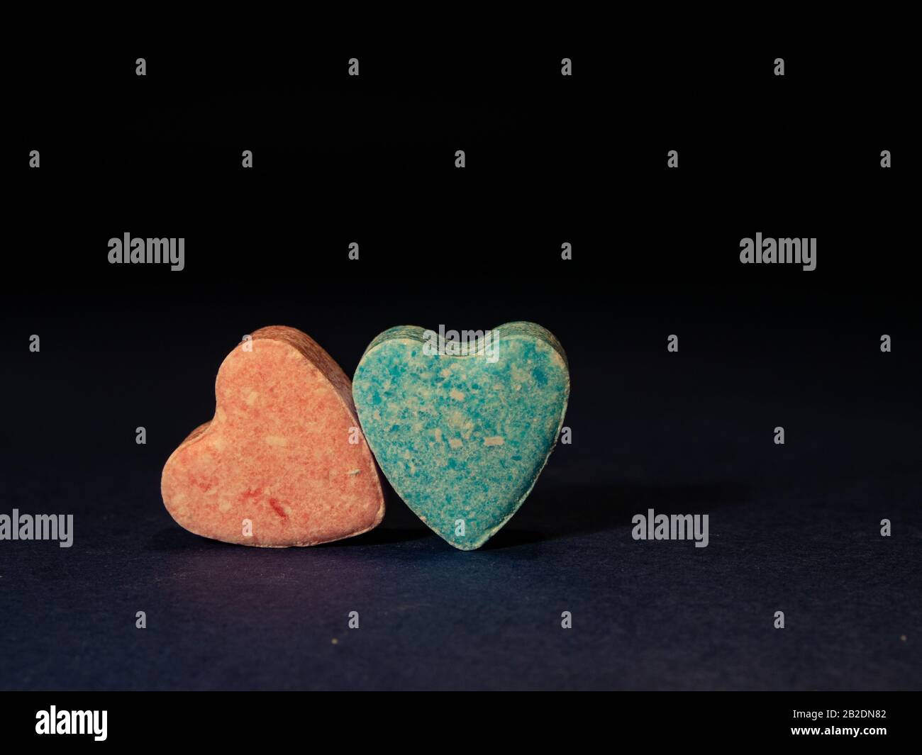 Dos caramelos con forma de corazón sobre fondo negro. Foto de stock