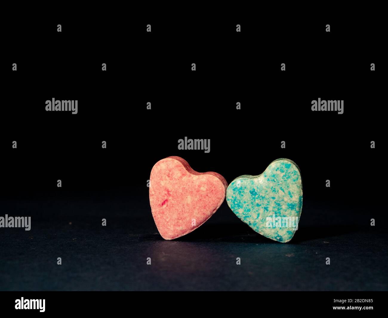 Dos caramelos con forma de corazón sobre fondo negro. Foto de stock