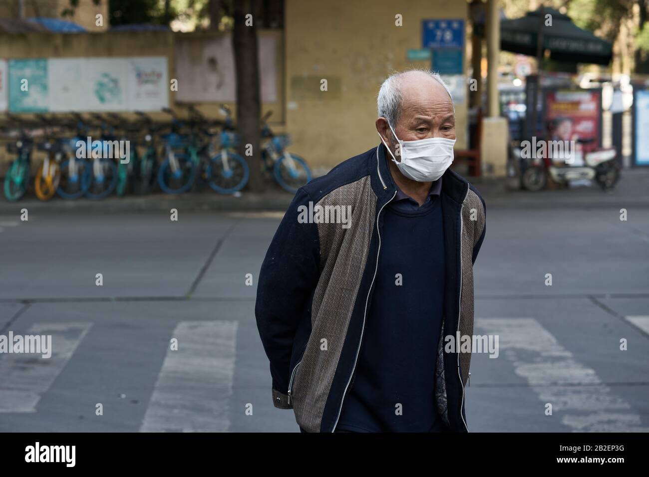 Durante el brote de la enfermedad de coronavirus que se extiende al planeta, un anciano llevaba una máscara quirúrgica en la calle para prevenir la enfermedad de coronavirus. Foto de stock