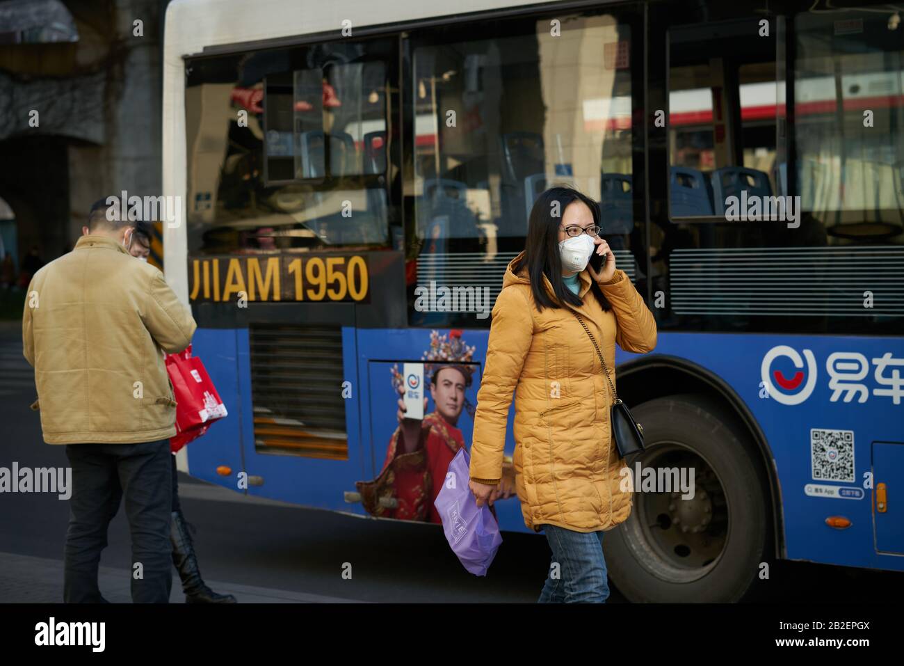 Durante el brote de enfermedad de coronavirus que se extiende al planeta, las personas están usando una máscara quirúrgica en la parada de autobús para prevenir la enfermedad de coronavirus. Foto de stock