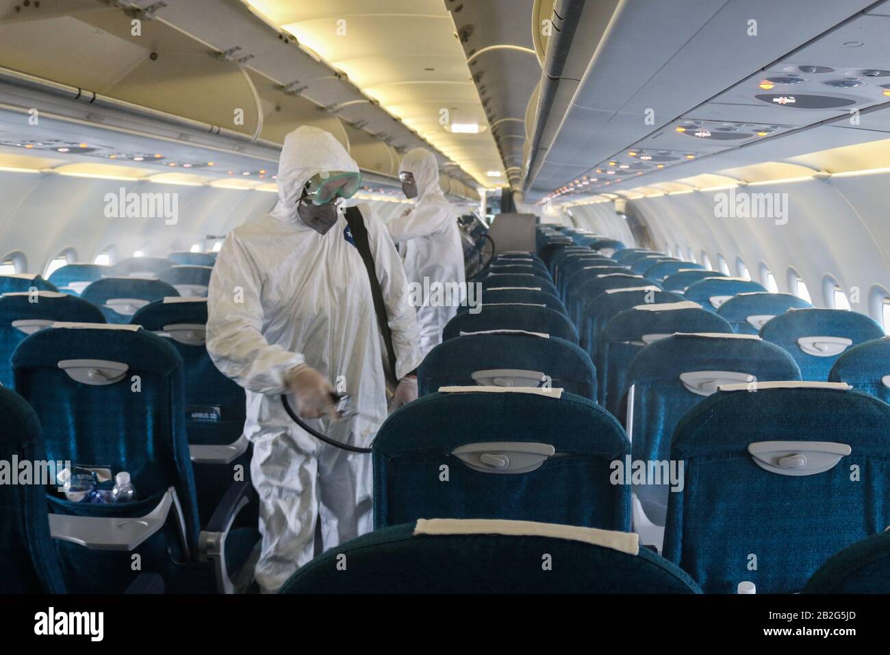 Hanoi, Vietnam. 3 de marzo de 2020. Miembros del personal del Centro para  el Control de Enfermedades en Hanoi pulverizan desinfectante dentro de un  avión en el Aeropuerto Internacional Noi Bai en
