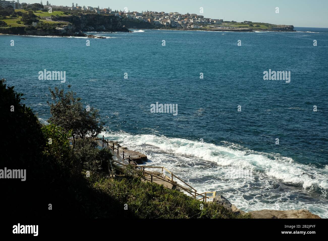 Con vistas a la piscina de mujeres McIver's, árboles y arbustos, la bahía de Coogee hasta Bondi, un paisaje costero de Sydney Foto de stock