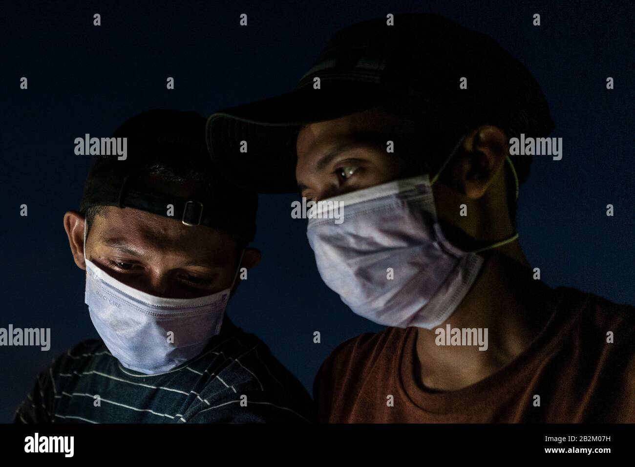 Hombres que llevaban máscaras protectoras mientras paseaban por las zonas públicas como medida preventiva contra la amenaza. El gobierno indonesio confirmó los primeros casos de dos mujeres indonesias positivas a coronavirus que fueron infectadas por un viajero extranjero y que ahora están siendo tratadas en el hospital de infección de Sulianti Sarosa en Yakarta. Indonesia es un país que mantiene estrechas relaciones económicas con China, incluyendo ser uno de los diez principales destinos turísticos de Wuhan, el epicentro de la epidemia. Foto de stock