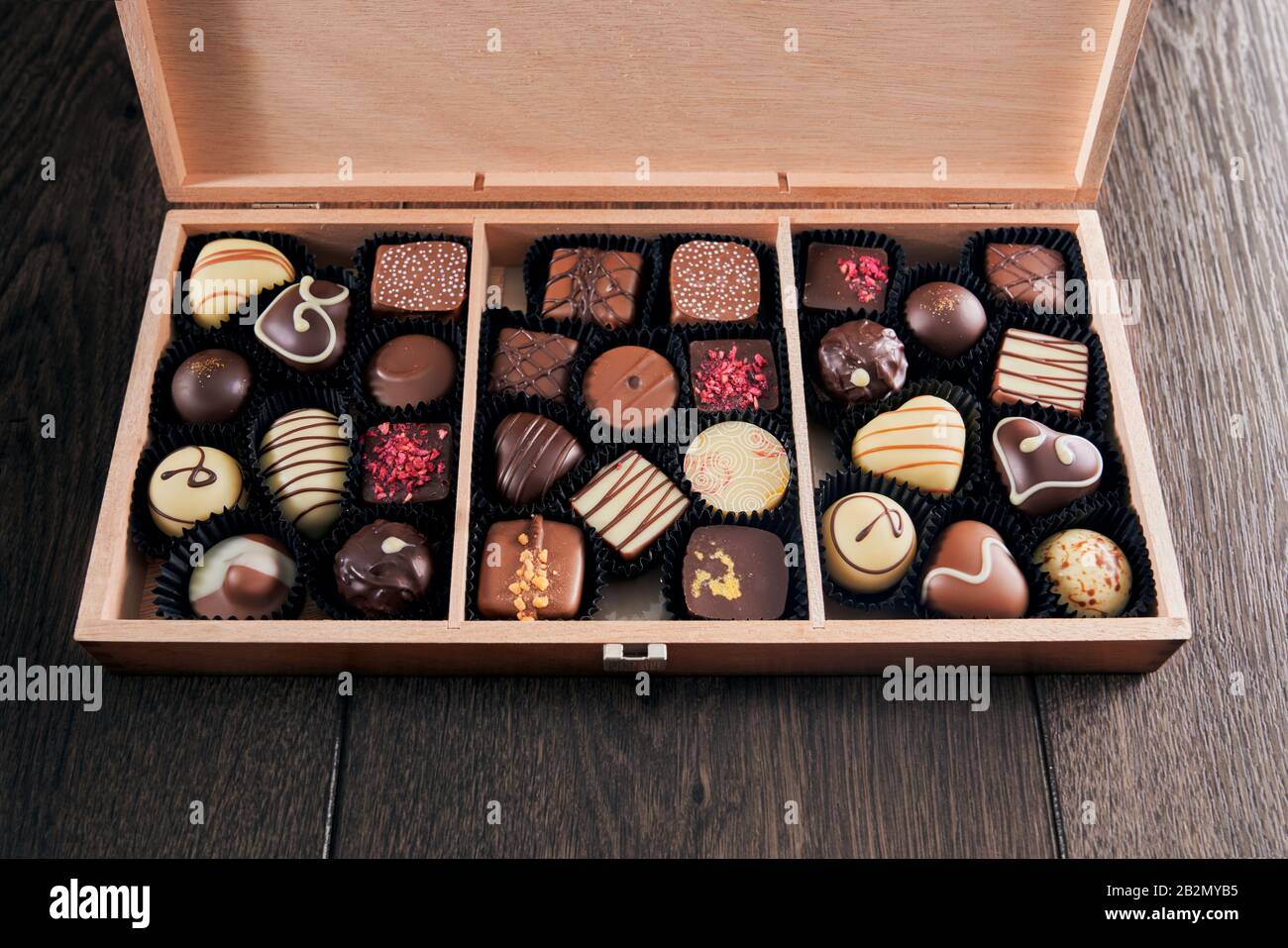 Desde la vista superior de dulces de chocolate variados en caja de regalo  de madera aislada en la mesa. Primer plano de deliciosos dulces con sabor  diferente. Concepto de comida Fotografía de