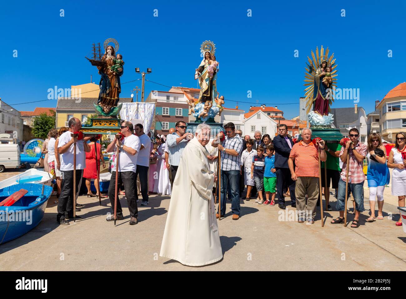 Sacerdote de aldea y las estatuas de la Virgen María en una procesión religiosa en Corrubedo, Galicia, España Foto de stock
