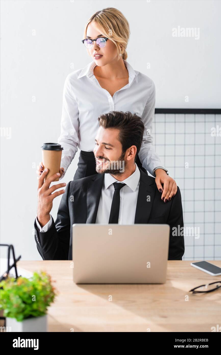 secretario atractivo dando café a un hombre de negocios sonriente Foto de stock