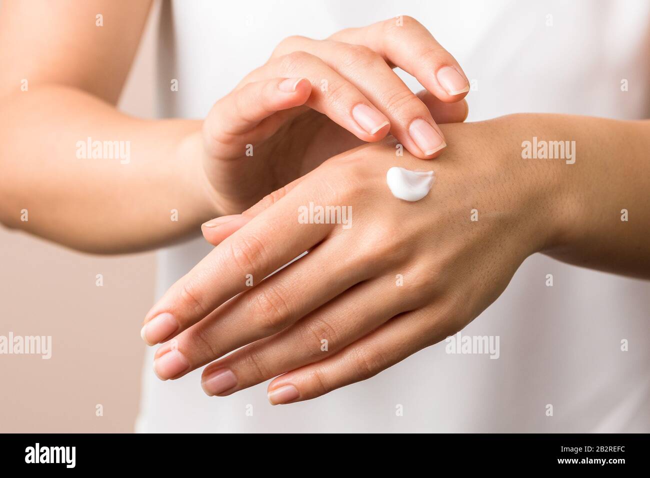 Mujer madura en albornoz aplicando crema de manos para hidratar las manos  después de la ducha