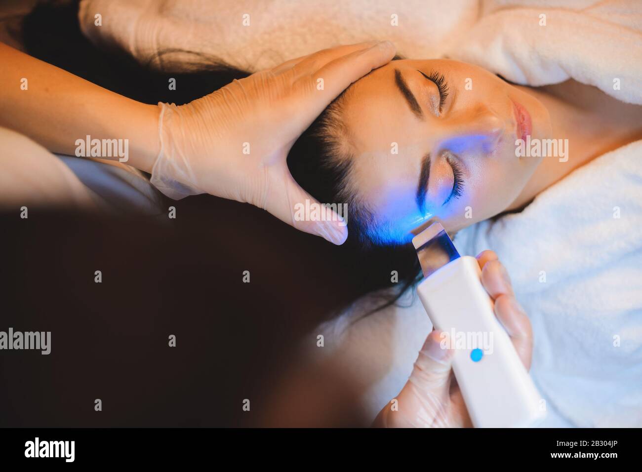 Un dermatólogo cuidadoso está teniendo una sesión de láser con una señora caucásica morena Foto de stock