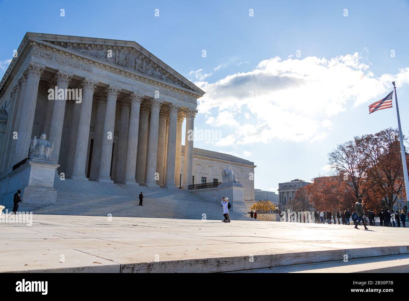 Corte Suprema de los Estados Unidos en el soleado día en D.C. con la bandera de los Estados Unidos agitando bajo la luz del sol. Foto de stock