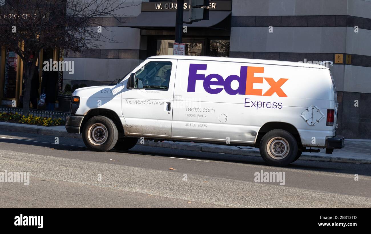 FedEx Express Van da vuelta a una calle del centro durante un día soleado en D.C. Foto de stock