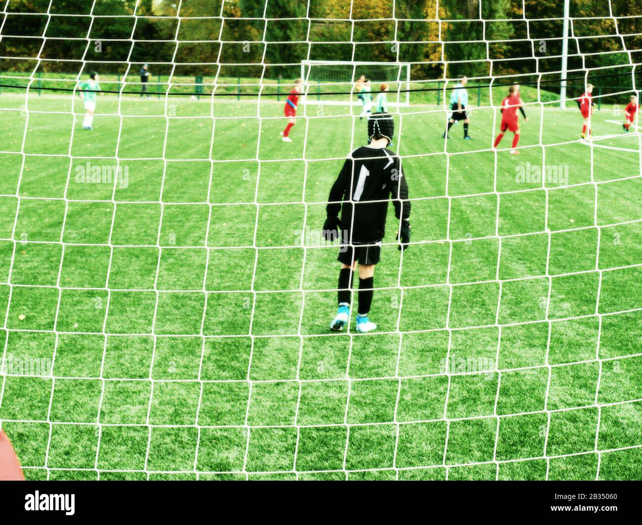 Equipo de jóvenes futbolistas en el campo de juegos vistos a través del portal Net. Foto de stock