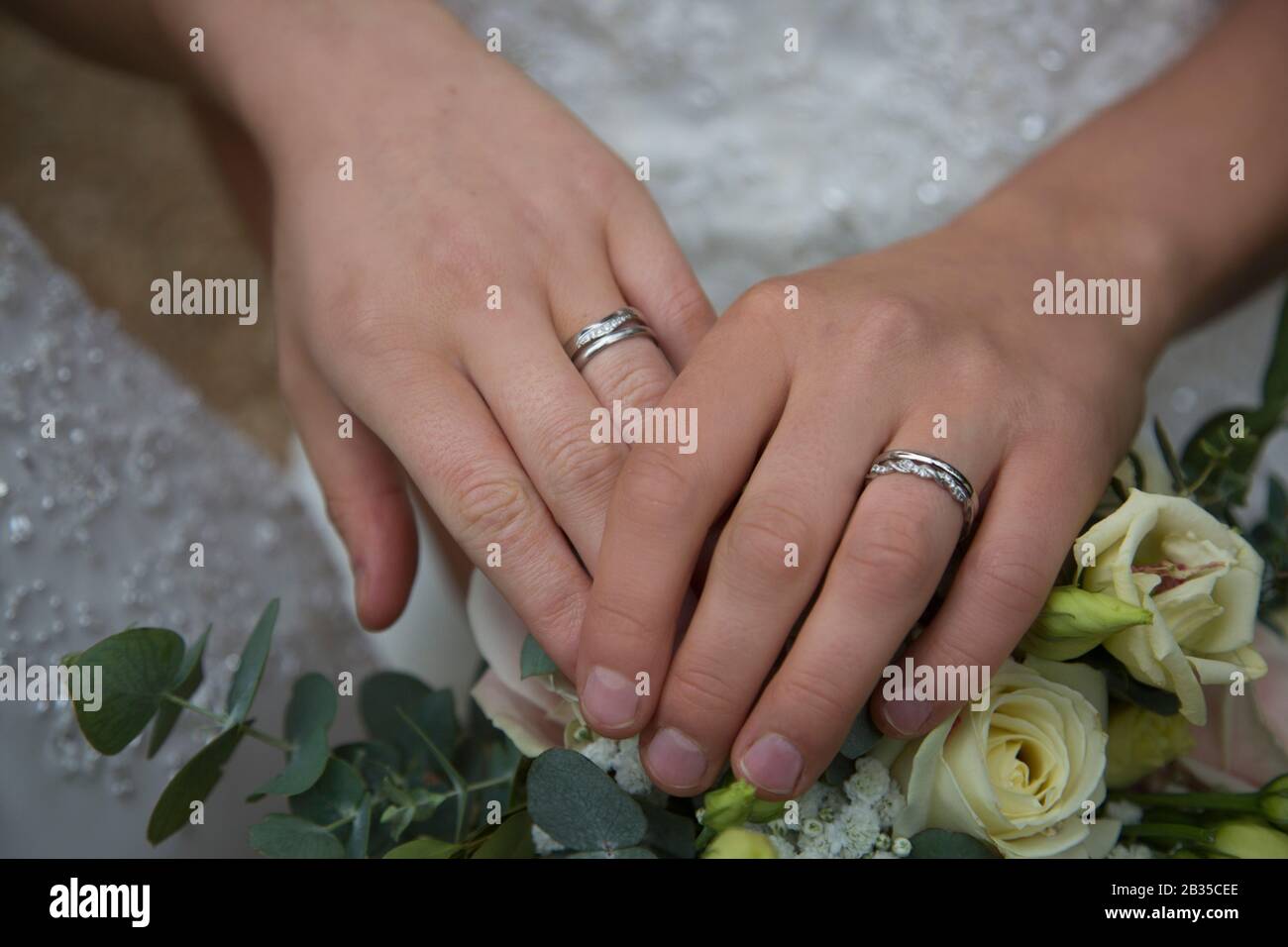 Dos novias manos con sus anillos de boda en el día de su boda, el matrimonio  gay en Inglaterra Fotografía de stock - Alamy